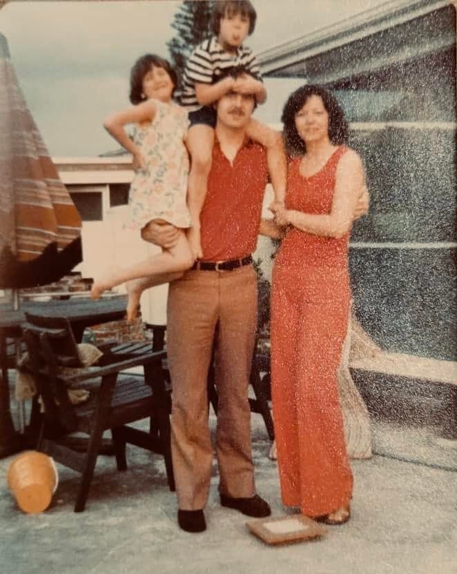 A family of four posing together beside a camper
